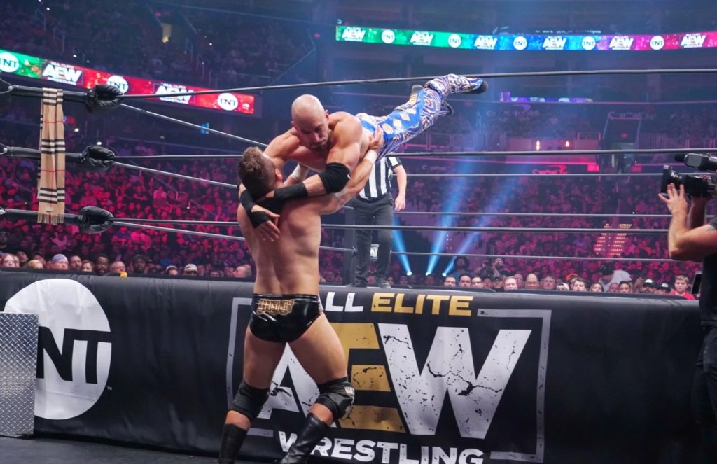 At this point in AEW history, MJF was somehow still a fan favorite and on the face side of things, despite clearly being a natural heel. He was the best friend of Cody Rhodes, and clearly being groomed as one of the future mega stars of AEW. Of course he’d be around for the first episode of AEW Dynamite, and his opponent would be the good friend of The Young Bucks, Brandon Cutler. MJF Rips Into Brandon Cutler In More Ways Than One As MJF made his way to the ring, he’d ask for his music to be cut. He’d remind fans they’re looking at the fastest rising and youngest star in the history of professional wrestling, only to be met with asshole chants. They’d get the rare chance to watch a star be born, as he faced Brandon Cutler, who got lost on his way to his seat. Cutler & MJF would lock up, and MJF would be incredibly cocky, only using one arm and shoving Cutler into the corner before tripping him. MJF would throw Cutler into the corner, only to have Cutler flip over him and slap him across the ear. He’d rush towards MJF and be sent onto the apron, only to come back in with a sunset flip for a two count. Cutler picked MJF up for a Death Valley Driver, but a rake to the eyes stopped this. MJF slipped to the outside, prompting Culter to go after him, only to have his arm stretched over the top rope, before sending him shoulder first into the ringpost. Cutler would be body slammed onto his arm, and one armbar would be able to end this, but MJF took his time and kept beating down Cutler. MJF would regret this, as he’d be sent to the outside and hit with a Magic Missle and have punches rained down on him. Cutler went up top after throwing MJF back in the ring, but lost his balance and slipped down. MJF would hit a hard elbow and lock in the Salt Of The Earth armbar, winning this match. Cutler never recovered from this loss, going winless for all of his AEW run to this point. Where Are They Now? MJF would go on to remain undefeated for nearly a year, until he faced Jon Moxley for the AEW Championship at All Out in 2020. Brandon Cutler is still looking to get his first win in AEW, feuding with another man who never got a win, Peter Avalon. They had me one on one during an episode of AEW Dark, but it ended in a double countout. Did you expect MJF to become the huge name he is today during this first episode? Let us know what you think in the comment section down below. SUBSCRIBE NOW: Get TheOvertimer’s Hottest Stories, Breaking News and Special Features in your email, CLICK HERE!